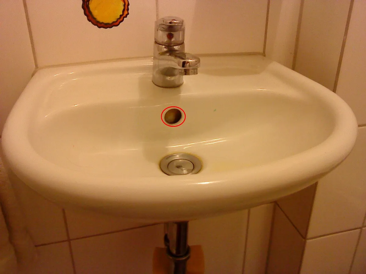 White bathroom basin with the overflow opening visible below a chrome faucet